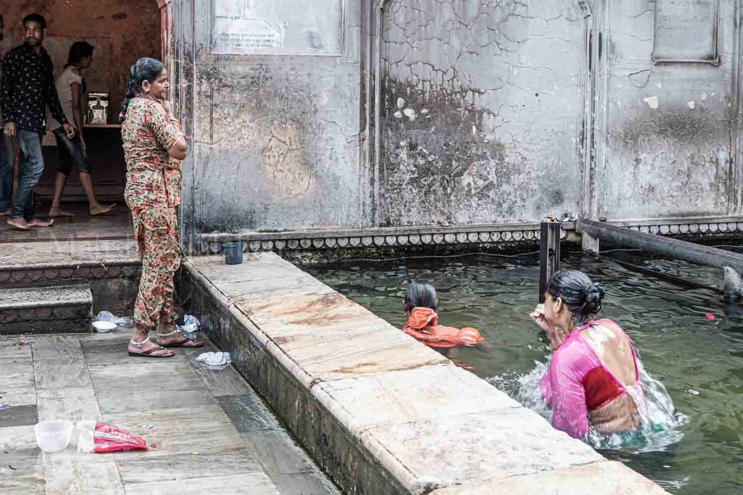 women and men take shower in pool of the temple.